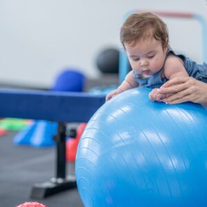 Child balancing on a beam with guidance from a therapist, focusing on strength and coordination, highlighting active and engaging physical therapy services.