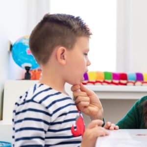 Child engaged in play-based therapy, pointing to lips for articulation treatment, highlighting interactive and supportive speech and language services.